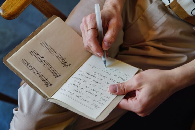 A person writing down song lyrics in a notebook